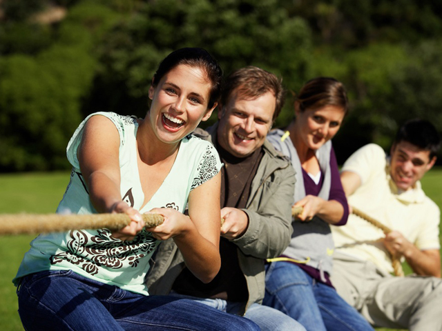  Friends playing tug-of-war in park (differential foco) 